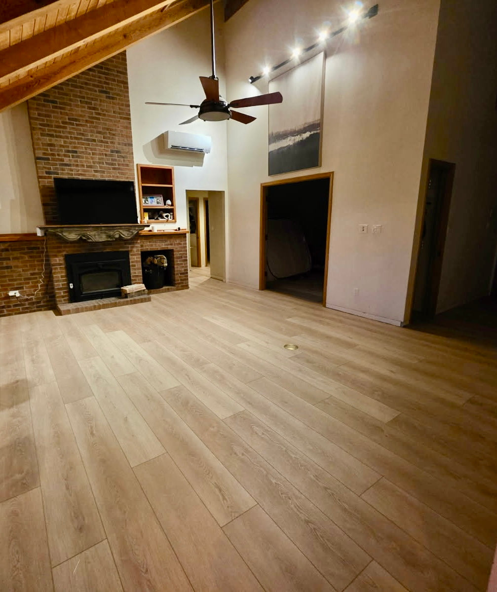 Living room with LVP flooring, brick fireplace, and ceiling fan.
