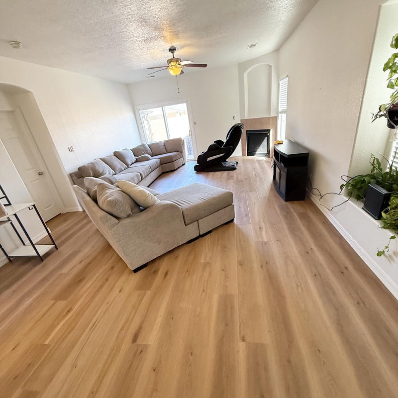 Living room with beige sectional sofa, wooden floor, and entertainment center.