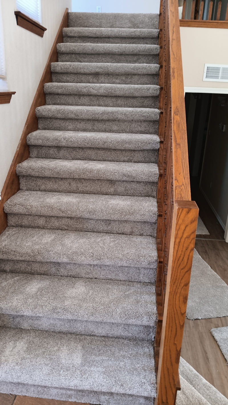 Carpeted staircase with wooden railings in a home setting