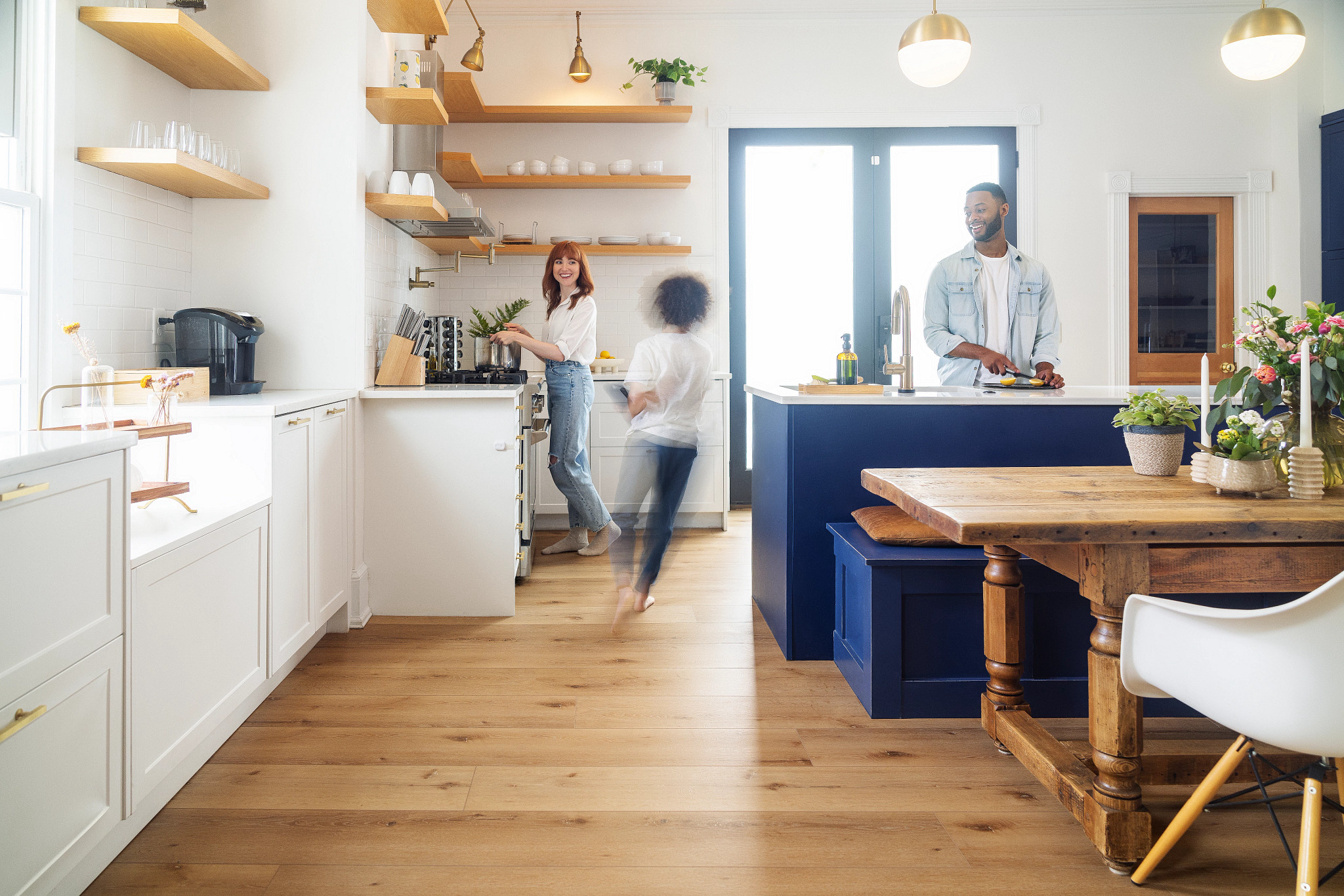 Family inside kitchen and child is running around on light brown COREtec wholesale floors