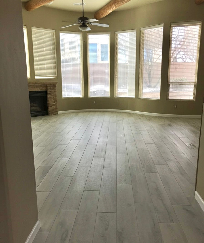 Living room with gray tile flooring, large windows, and a ceiling fan.