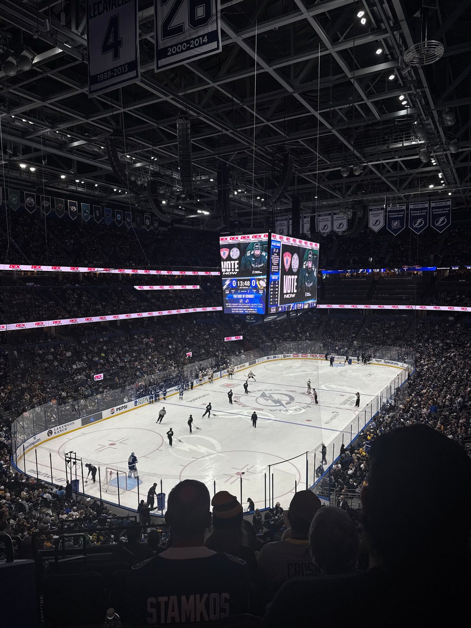 Hockey game in progress at a large indoor arena with fans and players on the ice.