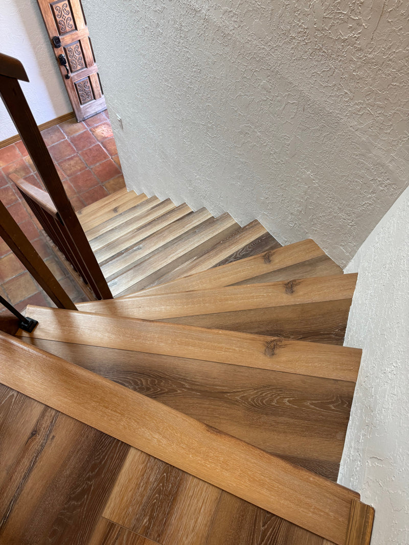 Wooden staircase with a textured wall and door in the background