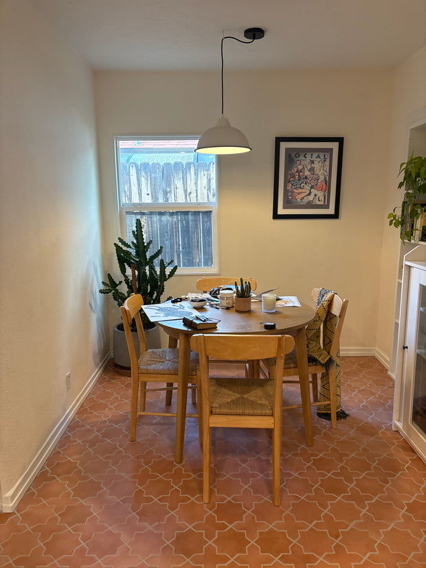 Dining area with a table and chairs near a window, wall lamp, and framed picture.