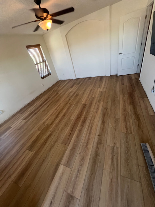 Room with wooden floor and white walls, ceiling fan visible.