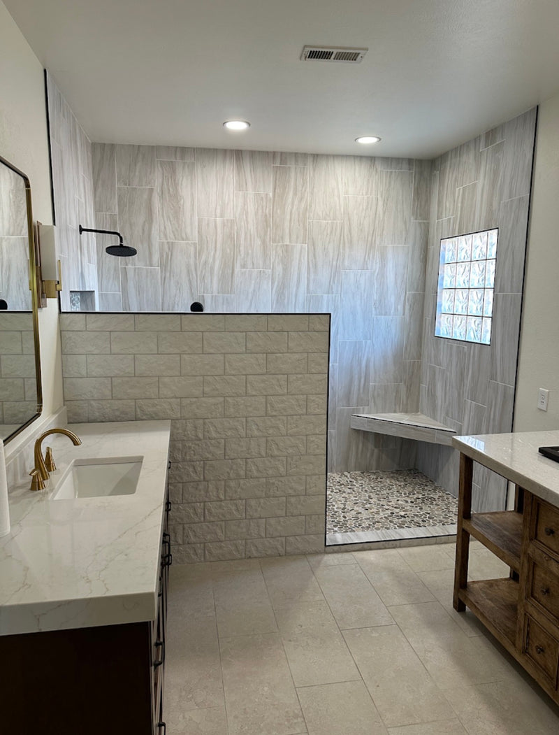 Bathroom with tiled walls, a shower, and a vanity.