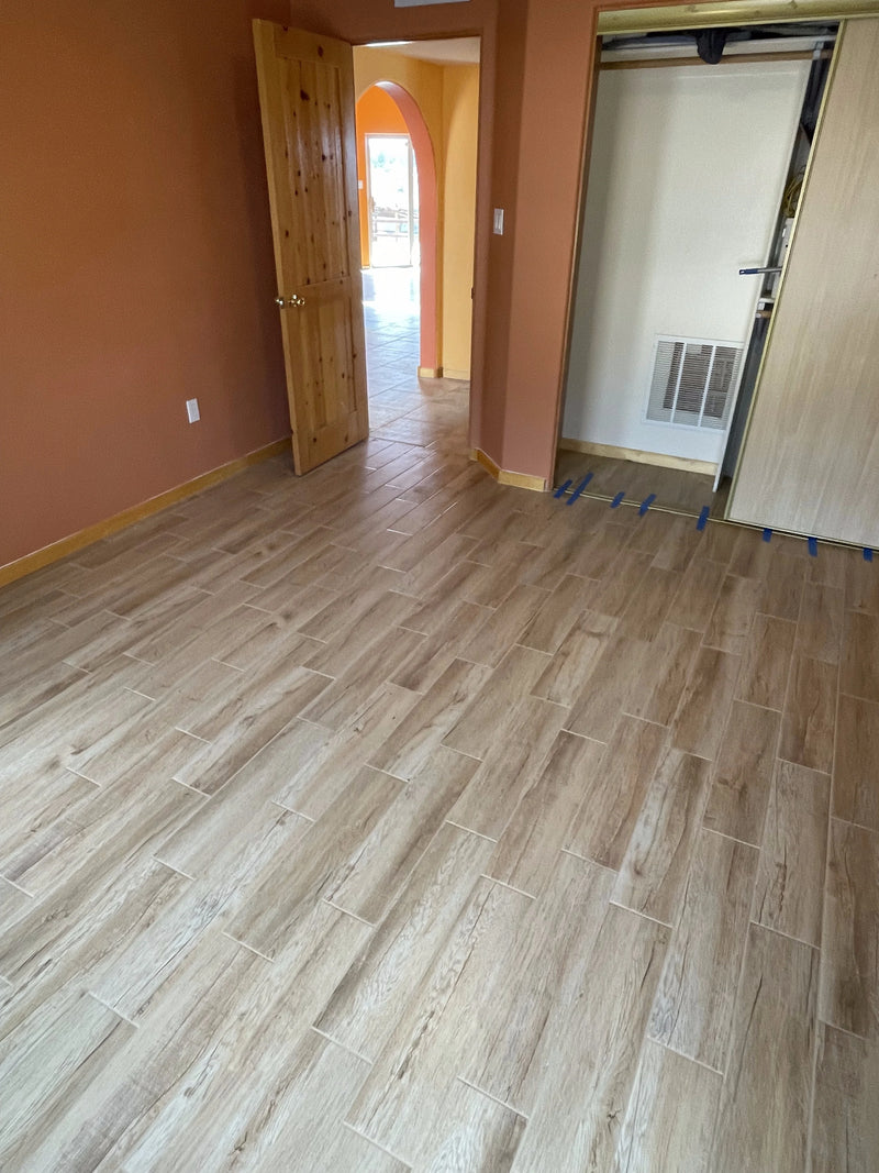 Room with wooden flooring and open door leading to another room.