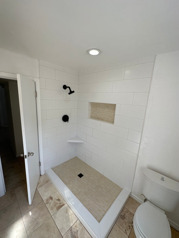 Bathroom with white tiled walls and a wooden floor.