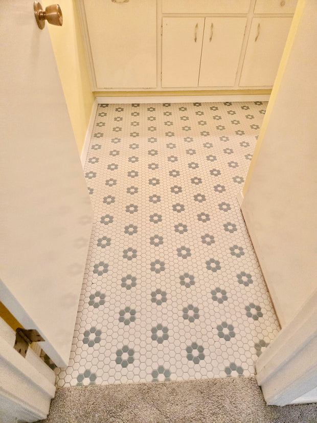 Patterned floor tile in a room with white walls and cabinets.