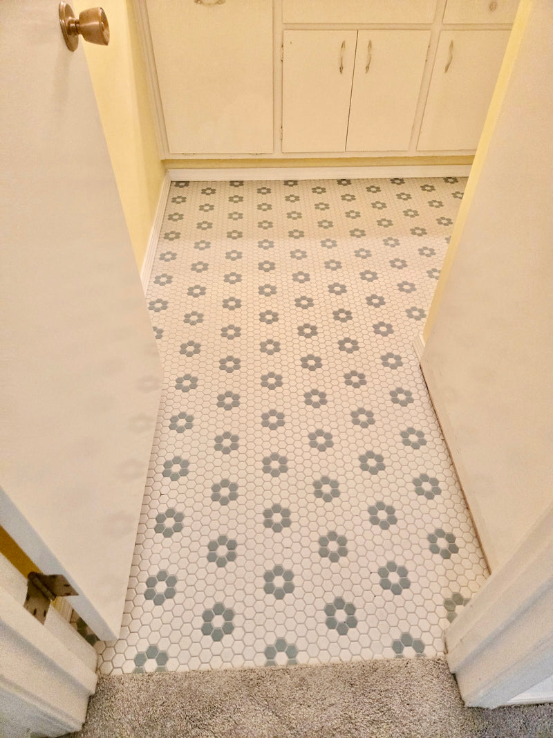 Patterned floor tile in a room with white walls and cabinets.